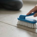 Person scrubbing tile grout with brush – Techniques section